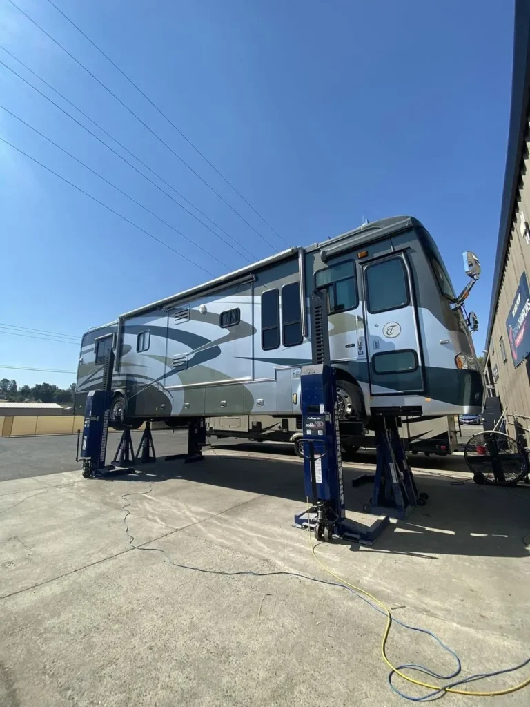 Class A motorhome raised on lifts for RV windshield replacement