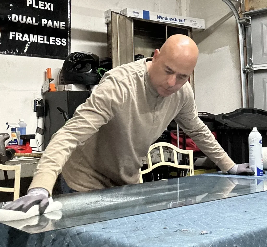 Technician cleaning a sheet of RV glass at the California RV Glass shop bench